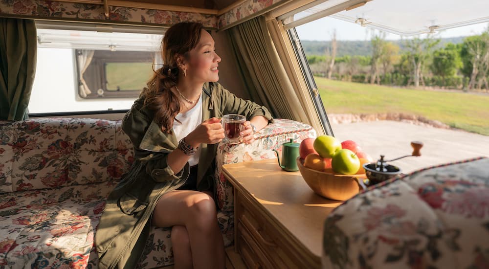 A person is shown sitting in an A-Frame camper.