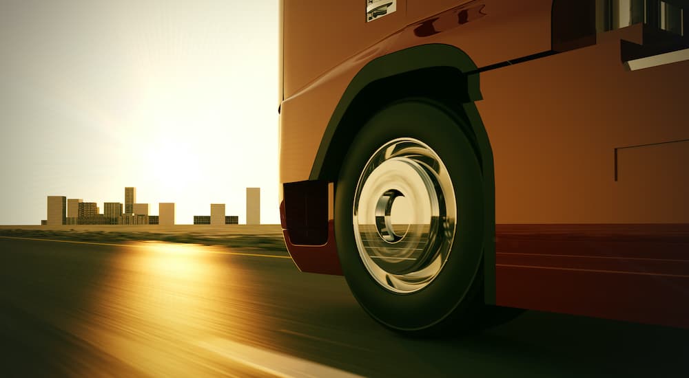 A large travel trailer is shown in close up as it drives past a city.