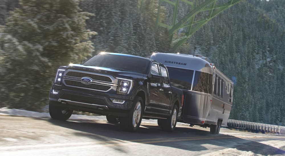 A black 2022 Ford F-150 is shown towing an airstream on an open road.
