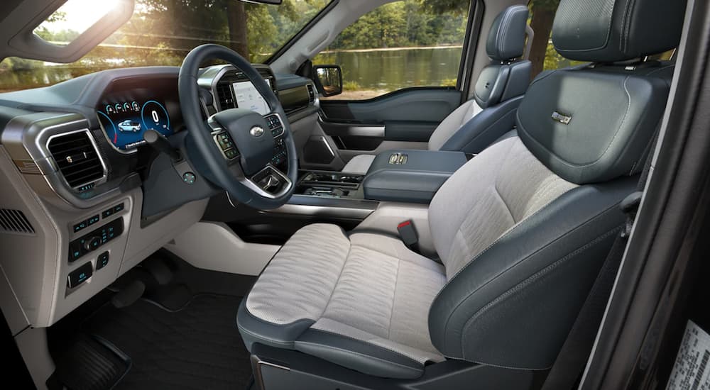 The black and white interior of a 2022 Ford F-150 shows the front seat and steering wheel.