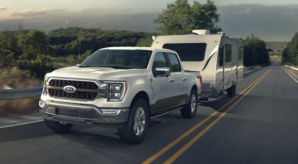 A white 2022 Ford F-150 is shown towing a trailer after winning a 2022 Ford F-150 vs 2022 Ram 1500 comparison.