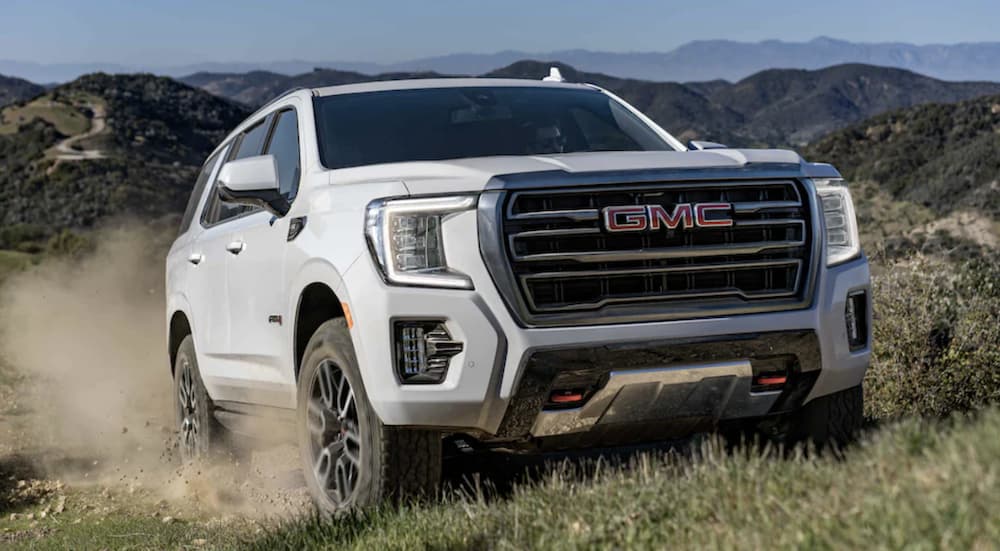 A white 2022 GMC Yukon is shown from the front off-roading on a hill during a 2022 GMC Yukon vs 2022 Nissan Armada comparison.