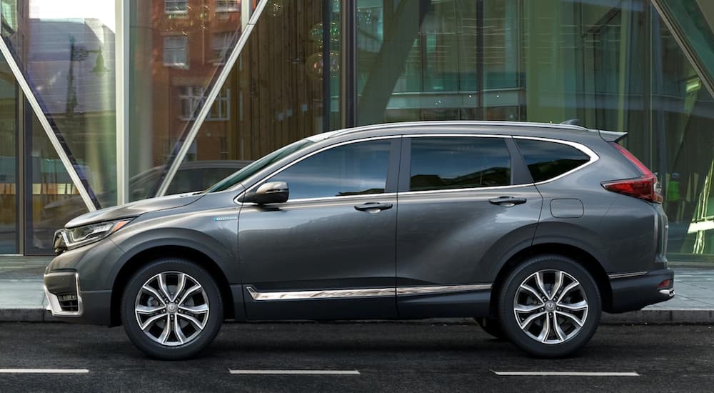 A grey 2022 Honda CR-V Hybrid Touring is shown from the side parked in front of a city building.