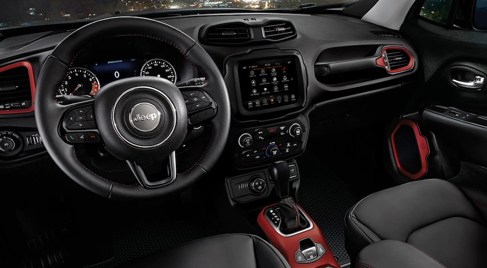 The black interior of a 2022 Jeep Renegade shows the steering wheel and infotainment screen.