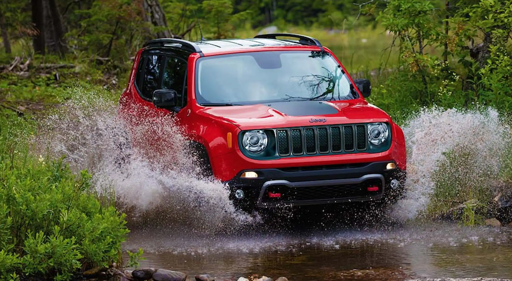 A red 2022 Jeep Renegade is shown off-roading through a river.