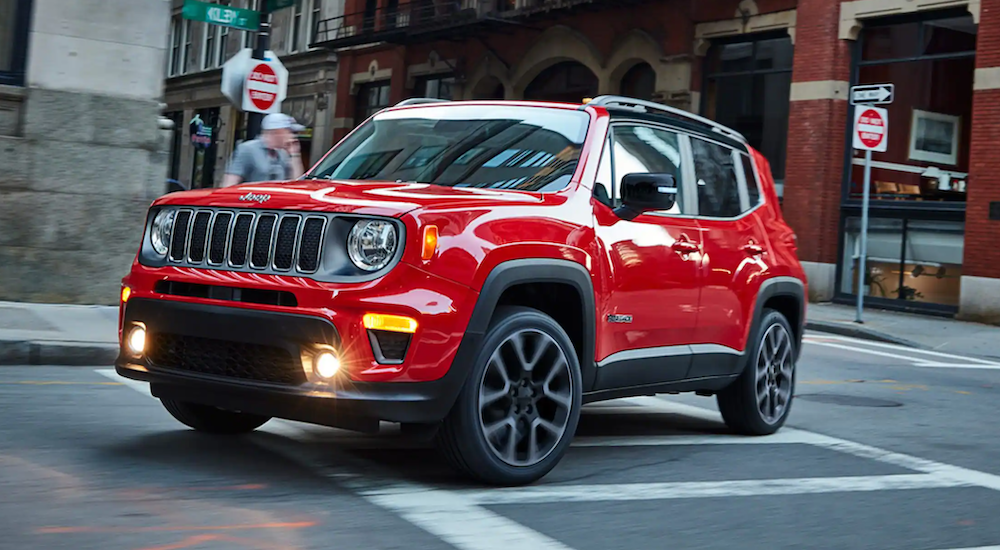 A red 2022 Jeep Renegade is shown from the side rounding a city corner.