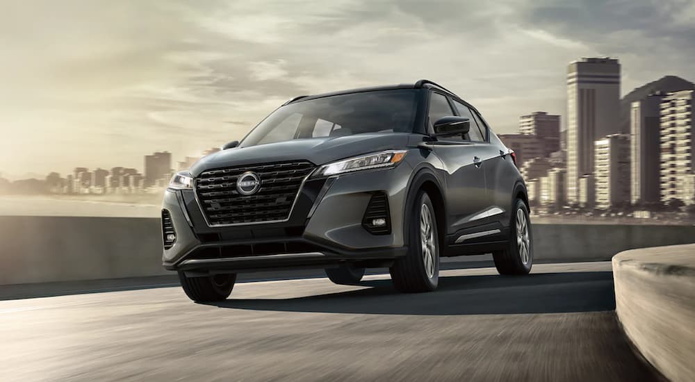 A grey 2022 Nissan Kicks is shown from the front driving on a city street.