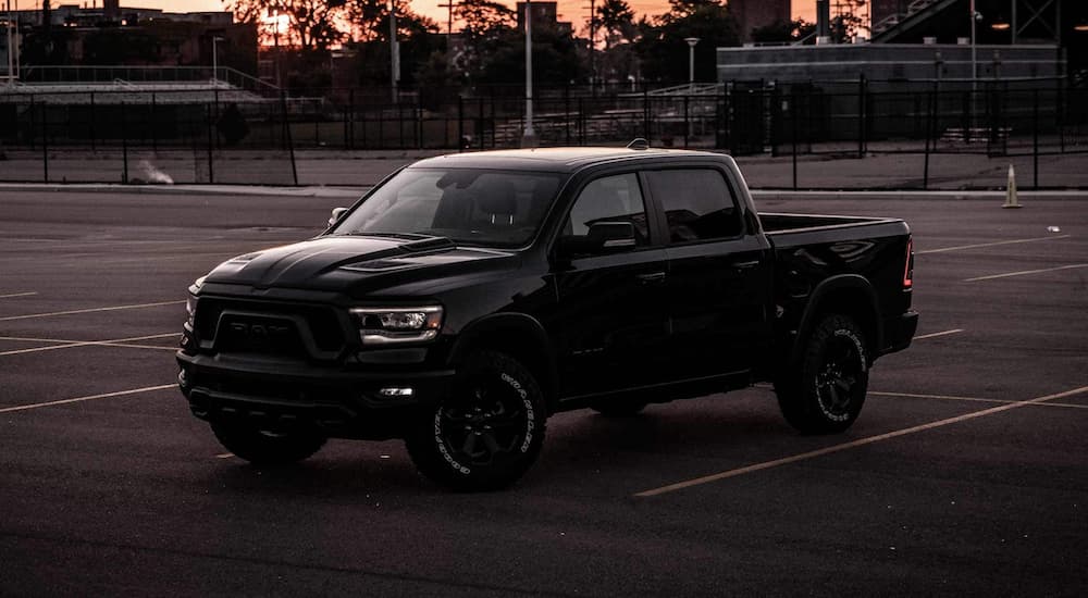 A black 2022 Ram 1500 is shown from the side parked in a parking lot at dusk.