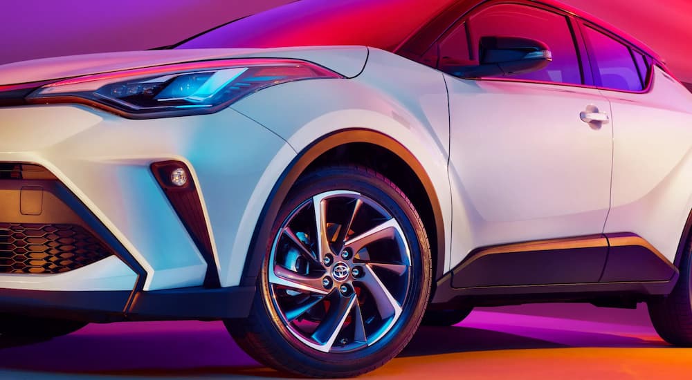 A close up of the side of a white 2022 Toyota C-HR shows the front headlight and tire.