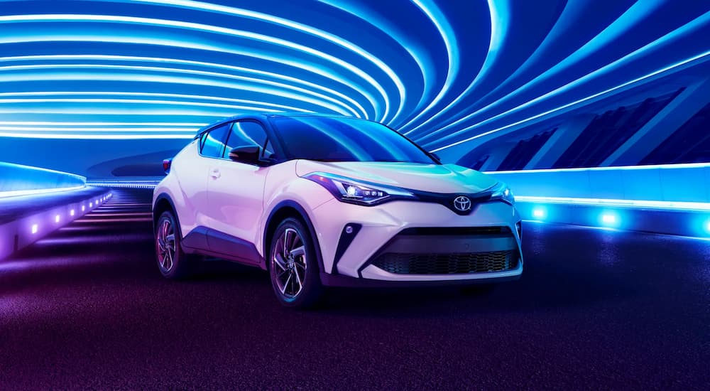 A white 2022 Toyota C-HR is shown parked in front of a blue lit background.