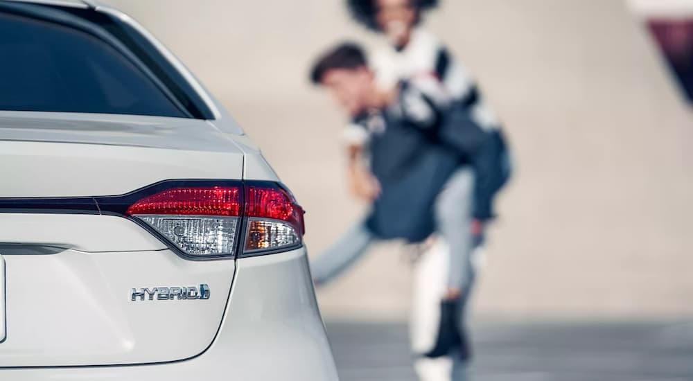 The Hybrid badge is shown in close up on a white 2022 Toyota Corolla Hybrid LE.