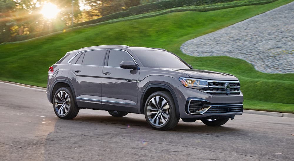 A grey 2022 Volkswagen Atlas Cross Sport V6 SEL Premium R-Line is shown from the side parked in front of a grass hill.
