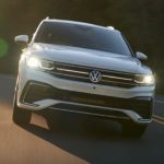 A white 2022 Volkswagen Tiguan SEL R-Line is shown from the front driving on an open road.