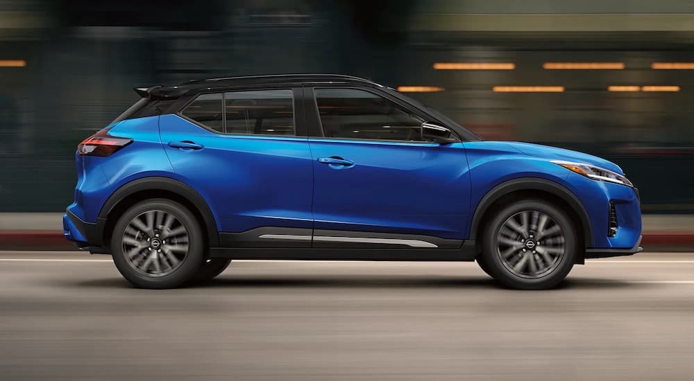 A blue 2022 Nissan Kicks is shown from the side while driving down a city street after leaving a Nissan dealer near you.