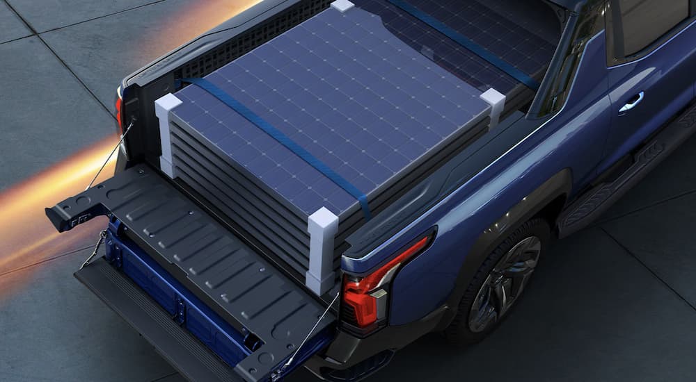 The bed of a blue 2024 Chevy Silverado EV shows a stack of solar panels.