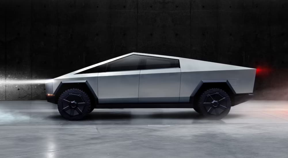 A silver 2023 Tesla Cybertruck is shown from the side parked in an air hanger.