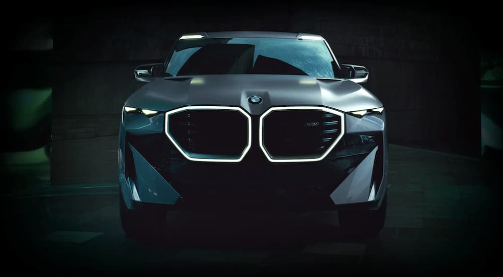 A concept BMW XM is shown from the front parked in a dark gallery at a BMW dealership.