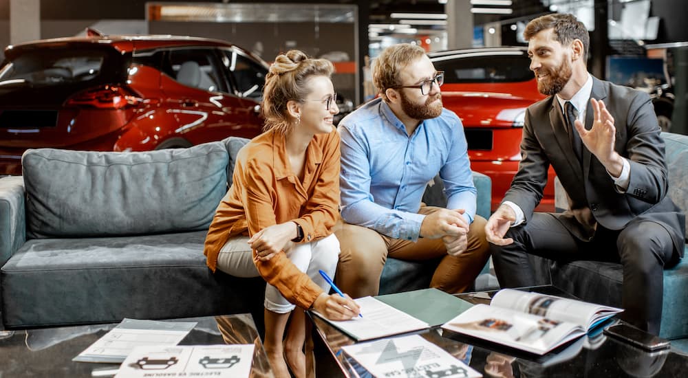 A couple is shown talking to a salesperson at a used Ford dealership.