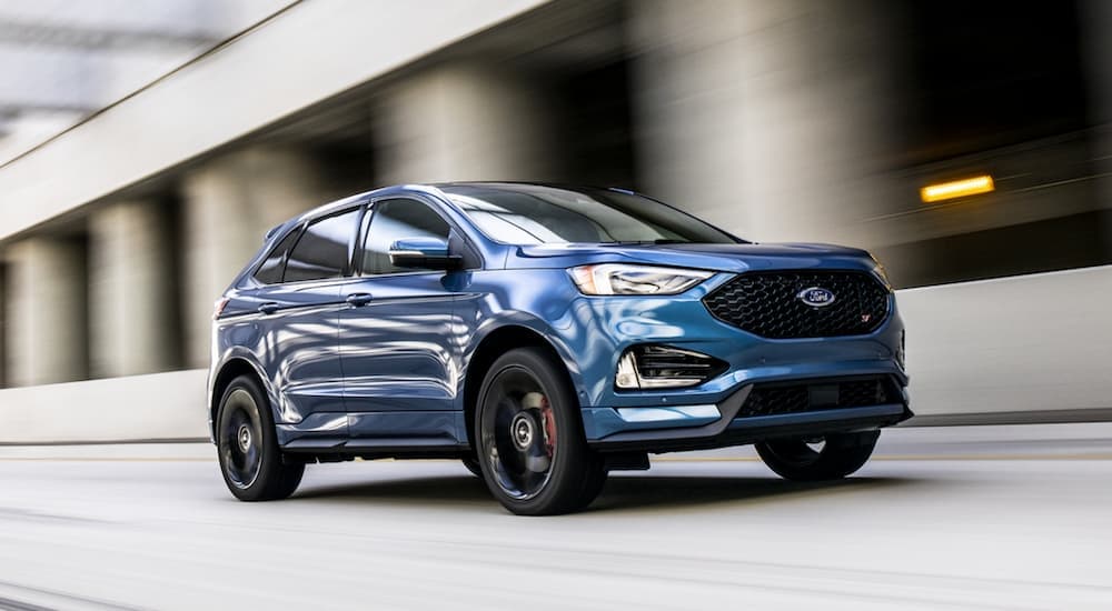 A blue 2020 Ford Edge ST is shown from the front driving on an open road.