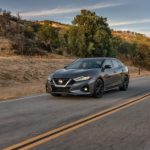 A grey 2020 Nissan Maxima is shown from the front driving on an open road.