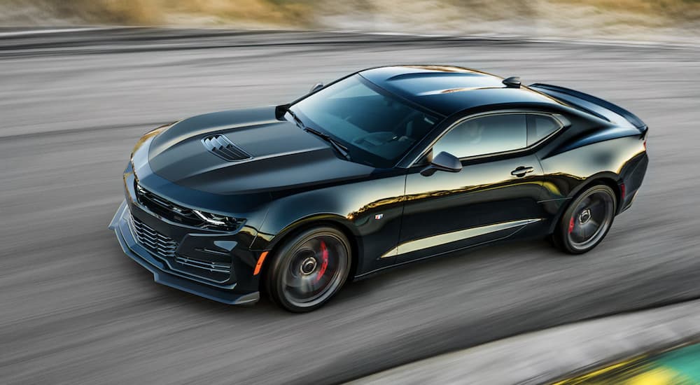A black 2022 Chevy Camaro is shown from the side driving on a race track.