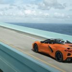 An orange 2022 Chevy Corvette is shown from the rear driving over a bridge after leaving a Chevrolet dealer.