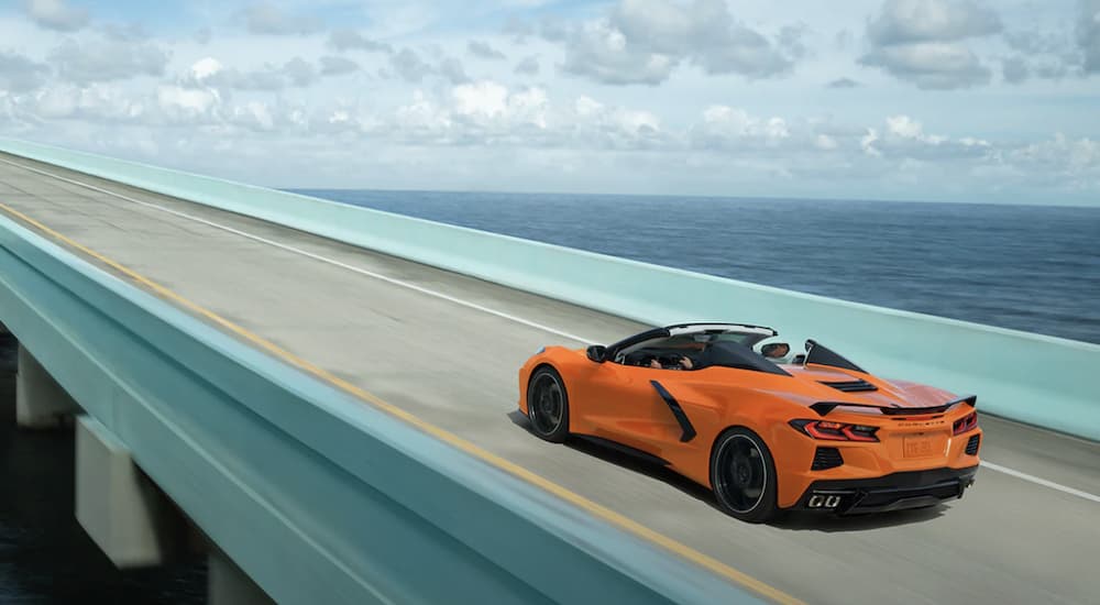 An orange 2022 Chevy Corvette is shown from the rear driving over a bridge after leaving a Chevrolet dealer.