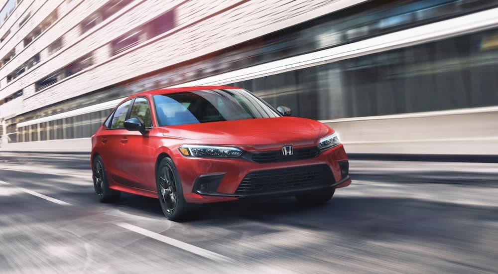 A red 2022 Honda Civic Touring is shown from the front driving through a city after visiting Classic Honda of Midland.