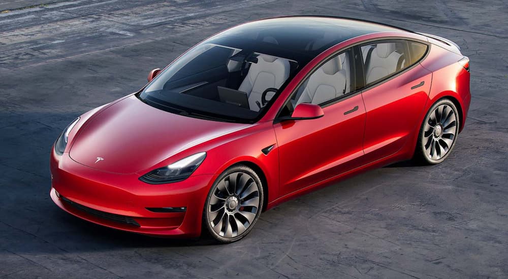 A red 2022 Tesla Model 3 is shown from above.