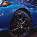 A closeup shows the driver side wheel from a low angle on blue 2022 Honda Civic.