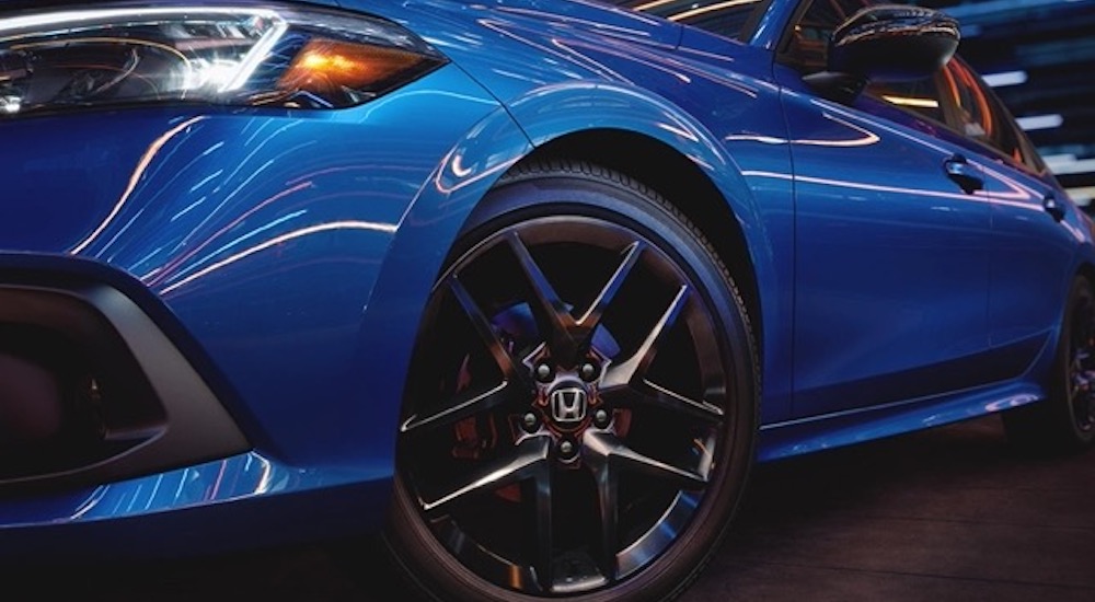 A closeup shows the driver side wheel from a low angle on blue 2022 Honda Civic.