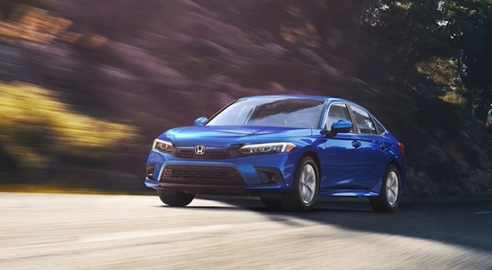 A blue 2022 Honda Civic is shown from the front at an angle while driving down the road.