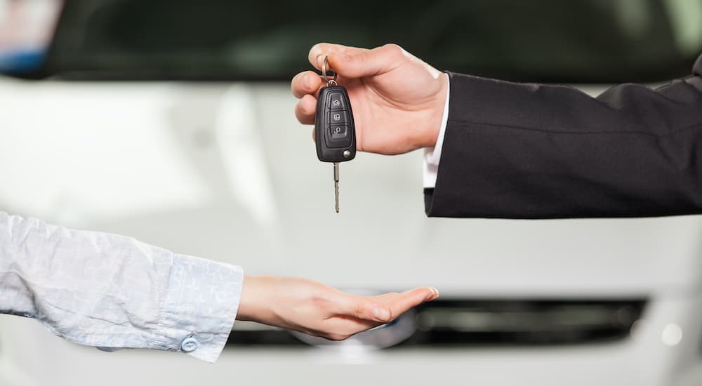 A person is shown passing a car key to a salesperson.