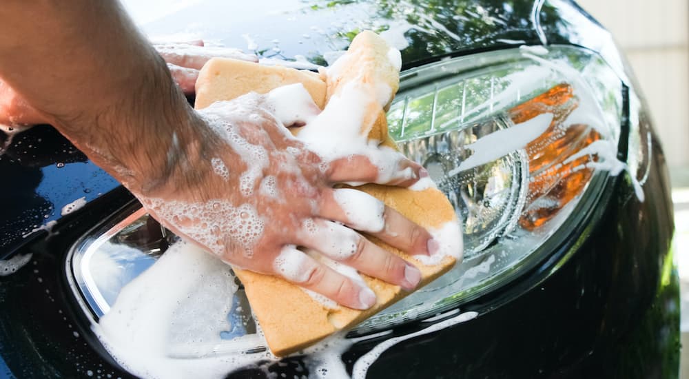 A person is shown washing a black car.