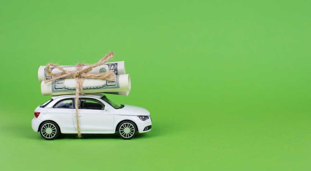 A roll of money is shown tied to the roof of a toy car.