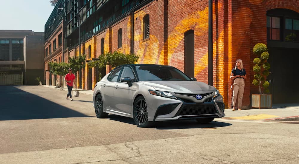 A silver 2022 Toyota Camry XSE Hybrid is shown on a city street.