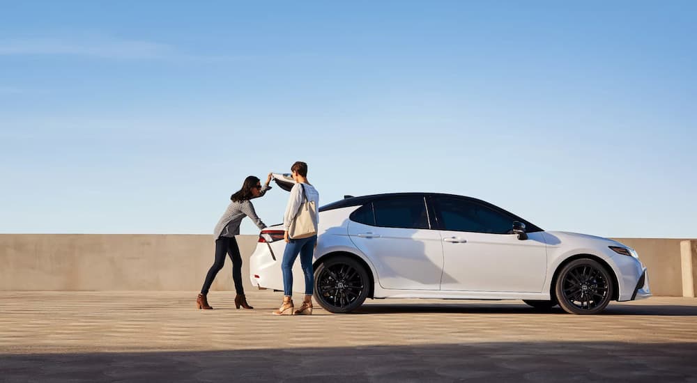 A couple is shown opening the truck of a white 2022 Toyota Camry XSE.