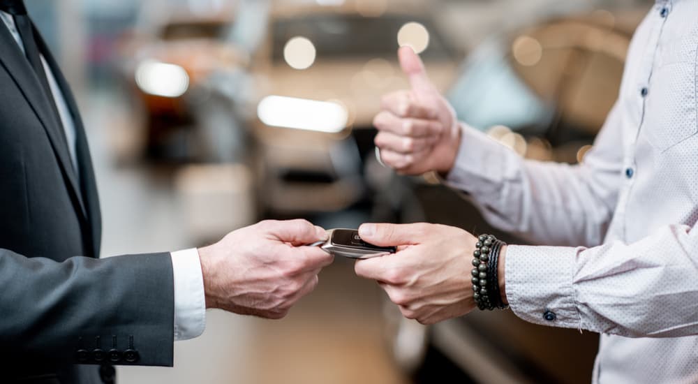 A customer is shown handing a car key to a car salesman during Toyota lease return.