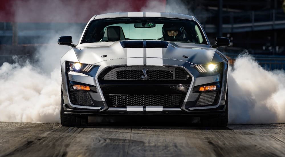 A grey 2021 Ford Mustang Shelby GT500 is shown doing a burnout after visiting a used Ford dealer.