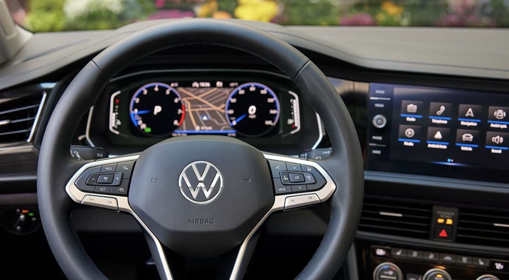 The black interior of a 2022 Volkswagen Jetta shows the steering wheel.