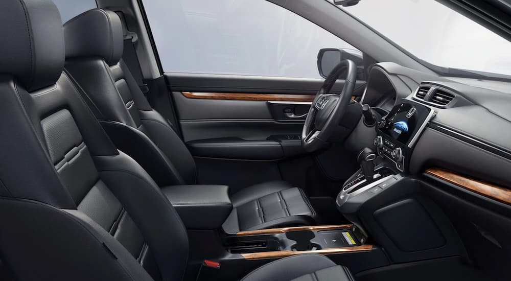 The black interior of a 2021 Honda CR-V shows the front seats and steering wheel.