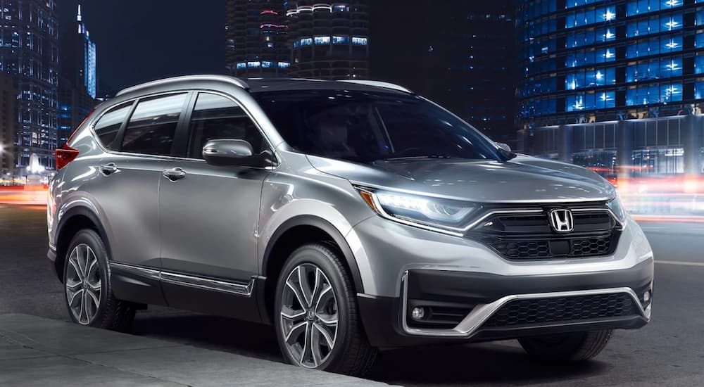 A silver 2021 Honda CR-V Touring is shown parked on a city street at night after leaving a car dealer.