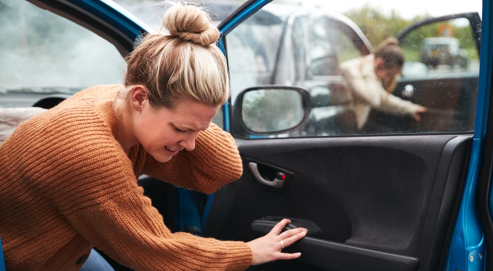 A woman is shown getting out of a car after a collision.