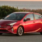 A red 2018 Toyota Prius is shown from the side parked in a parking lot.