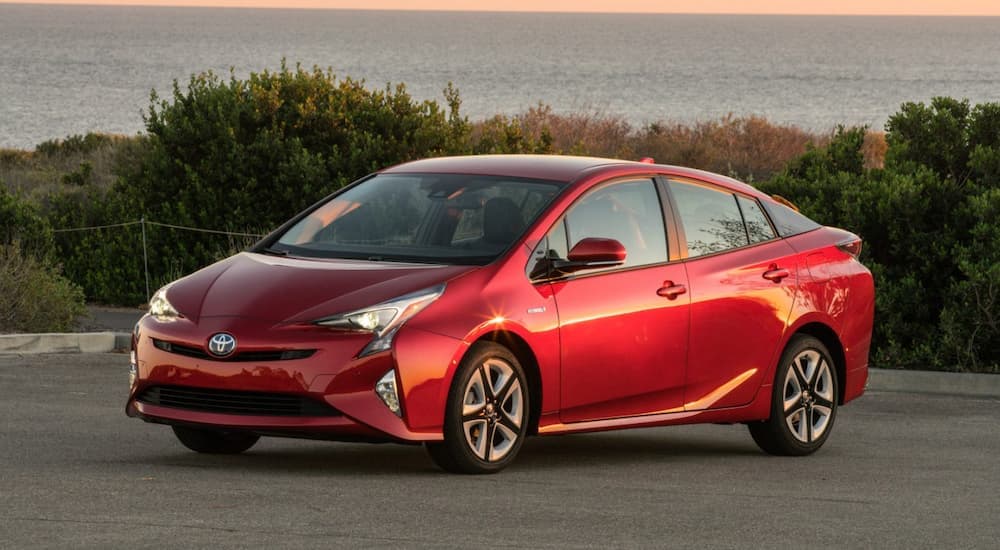 A red 2018 Toyota Prius is shown from the side parked in a parking lot.