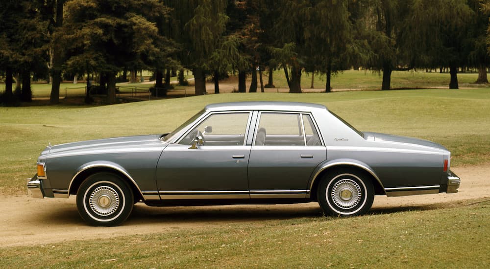 A grey 1977 Chevy Caprice is shown from the side parked in a field.