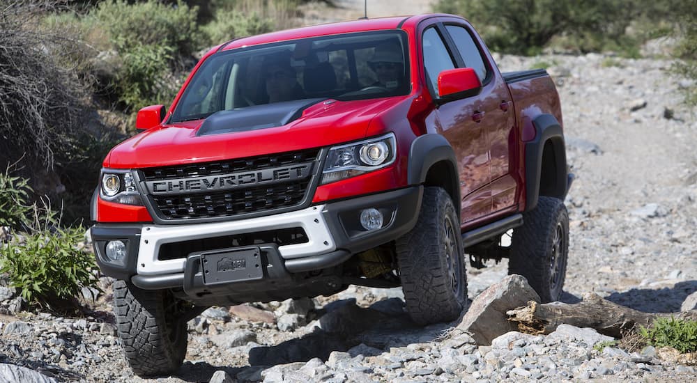 A red 2022 Chevy Colorado ZR2 Bison is shown from the front while it crawls over rocks during a 2022 Chevy Colorado vs 2022 Ford Ranger comparison.