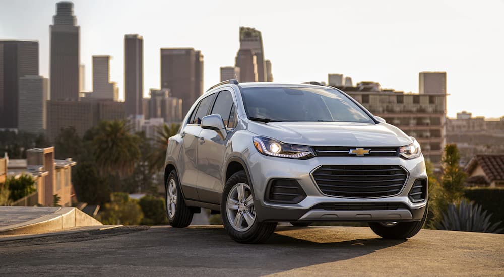 A silver 2022 Chevy Trax is shown from a front angle parked on a city hill during a 2022 Chevy Trax vs 2022 Kia Soul comparison.