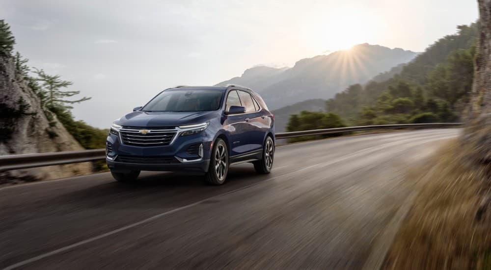 A blue 2022 Chevy Equinox is shown from the front at an angle while it drives on a mountain road.