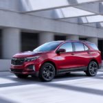 A red 2022 Chevy Equinox RS is shown from the side at an angle driving on a covered freeway during a 2022 Chevy Equinox vs 2022 Nissan Rogue comparison.